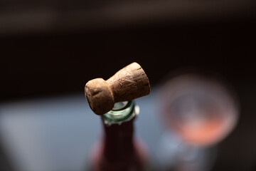 Cork on a bottle of pink champagne on a glass table by a window at sunset