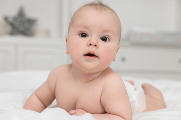 Cute baby lying on white bed at home