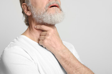 Obraz premium Senior man suffering from sore throat on white background, closeup view with space for text. Cold symptoms