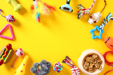 Flat lay composition with pet toys and accessories on yellow background. Pet care, training, grooming concept. Top view with copy space.