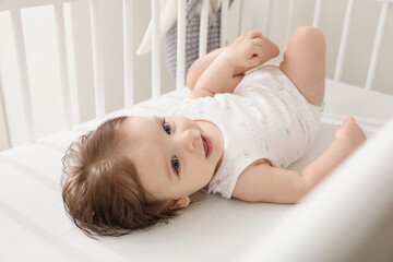 Obraz na płótnie Canvas Cute little baby lying in comfortable crib at home
