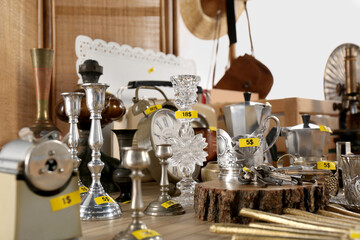 Many different items on wooden table indoors. Garage sale