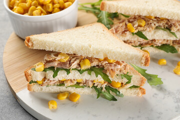 Delicious sandwiches with tuna, corn and greens on light grey table