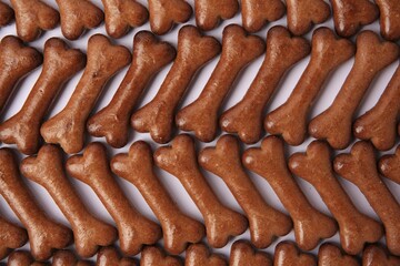 Flat lay composition with many bone shaped dog cookies on white background