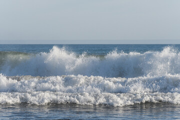 Wave breaking on the seashore splashing foam.