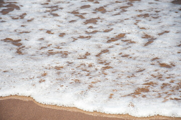 Fototapeta na wymiar Top view of the foam of a wave arriving at the seashore.