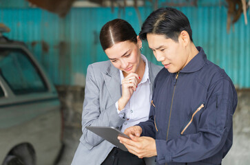 Mechanic and young woman client talking together at the repair garage, Female manager and auto mechanic in auto repair shop, Car repair and maintenance concepts