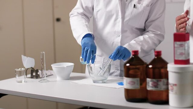 A liquid is filled in a glass bowl. The PTA wears gloves and the environment is sterile.