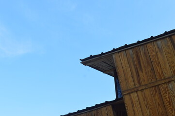 Low angle view of futuristic architecture, wooden villa, against bright blue sky and white clouds, with negative space.