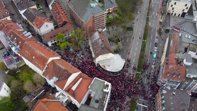 Aerial Drone view : Audience and fans of FCK Football Club marching into the Bars of old City ( Altstadt ) crowding, blocking the street intersection to celebrate their Match win ( Victory ) with beer