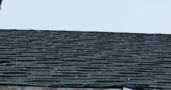 A hail storm sends hail down on top of a roof