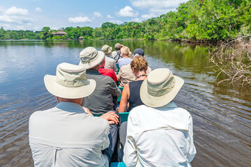 Tourist group arriving at Amazon rainforest lodge by canoe, Yasuni national park, Amazon river...