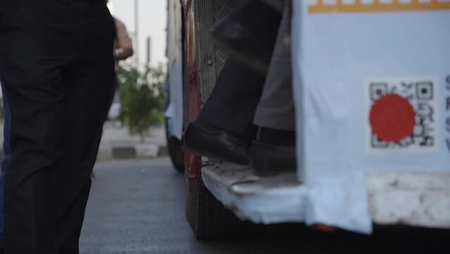 Slow motion of people boarding city bus, closeup of legs, India