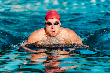 Swimming man - male swimmer swimming breaststroke. Portrait of man doing breast stroke swimming in...