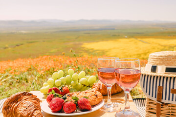 Rose wine, croissants and strawberry on the small table, Picnic on beautiful spring meadow