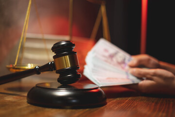 A Mallet or hammer of the judge with hand holding money as background. Concept of Law and justice...