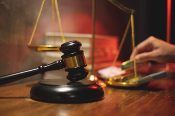 A Mallet or hammer of the judge with hand holding gold as background. Concept of Law and justice...