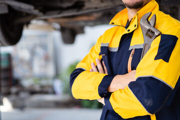 Fototapeta premium Professional caucasian white automobile technician holding a wrench and making crossed arms and looking at camera.