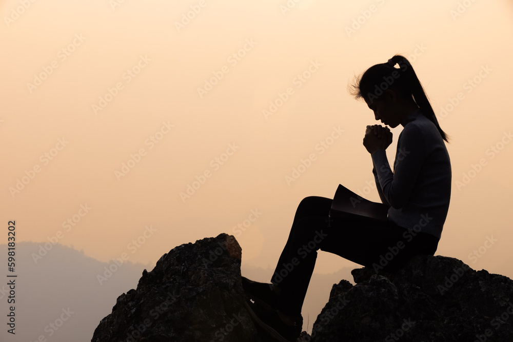 Wall mural Silhouette of a women is praying to God on the mountain. Praying hands with faith in religion and belief in God on blessing background. Power of hope or love and devotion. - Wall murals
