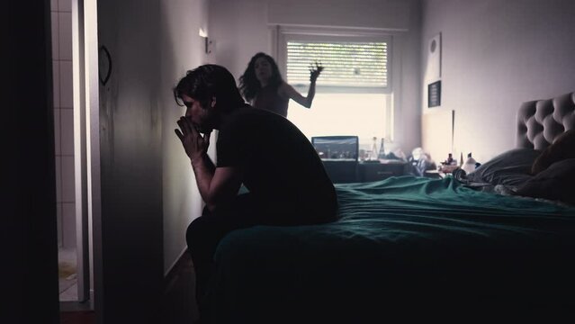 Couple Arguing and Fighting. Man feeling pressure by Female Partner. girlfriend in background discussing relationship while depressed man sits by the bedside feeling frustration