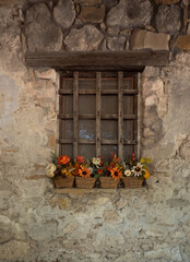 Fototapeta na wymiar Old Stone Building with Baskets of Fall Flowers on the Wooden Window Sill