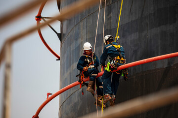 Male two worker rope down access safety inspection of pipe fire water repair storage tank