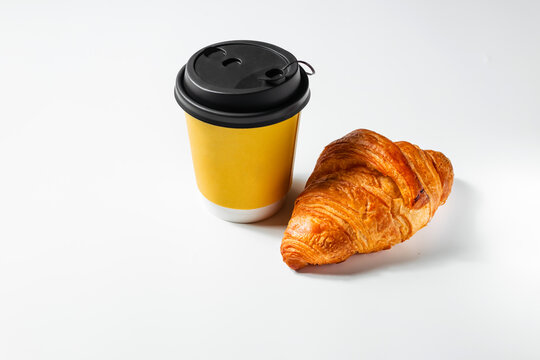 Banner with yellow cup of coffee with a croissant on a white background. Stylish takeaway hot drink concept. A delicious quick snack