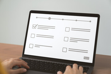 Hand using laptop and filling survey form online.