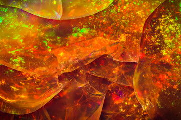 fire opal play-of-color. macro detail texture background. close-up raw rough unpolished...
