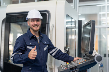 Male engineer operating cnc machine in control panel at factory. Smiling man technician in uniform...