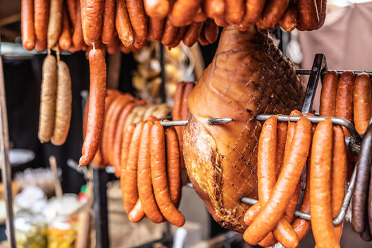 Cured meat products such as ham, sausages and frankfurters hanging at the market vendor booth outdoors