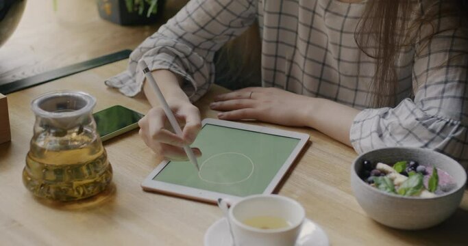 Close-up of female designer drawing with graphics tablet concentrated on creative work at cafe table. Freelance work and artists concept. Generative AI