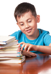 Child and books. The boy reads and plays with books. The kid steps up with his fingers on a pile of books. A preschooler is learning to read. Portrait of a boy on a white background
