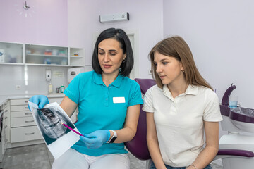 Obraz premium Dentist and patient choose treatment during consultation in beautiful clinic.