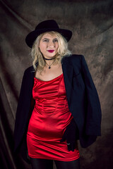 beautiful young woman wear elegant red dress and black hat isolated on dark background