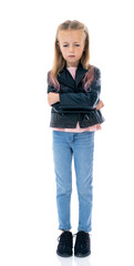 Full-length portrait of  dissatisfied five year old girl with arms crossed over looks down, isolated on white background. Small girl with irritated face in black leather jacket posing in studio.
