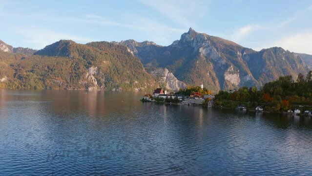4k drone forward video (Ultra High Definition) of Maria Kronung church. Aerial autumn scene of Traunsee lake. Incredible landscape of Austrian Alps with Traunstein peak on background, Austria, Europe.