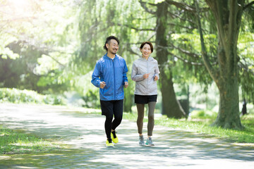 A couple running in a park with beautiful fresh greenery