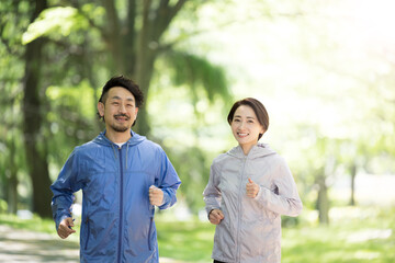 新緑の美しい公園の中ランニングするカップル　アップ