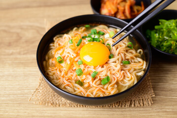 Asian instant noodle soup with fresh egg yolk eating with kimchi cabbage and seaweed salad