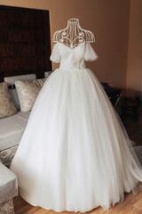 An exquisite wedding dress on a mannequin in the bride's room. High quality photo. Wedding details. White voluminous dress