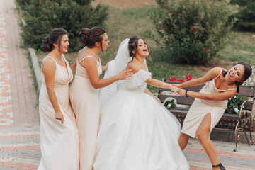 Wedding photo in nature. A brunette bride in a white long dress and her friends in nude dresses are...