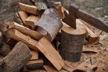 Still life. Close-up shot of a wood-burning ax and firewood for the winter in a rustic style. Ax and firewood in the yard or coniferous forest. Cutting wood in the forest for fire heat