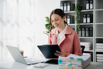 Beautiful woman using laptop and tablet while sitting at her working place. Concentrated at work.