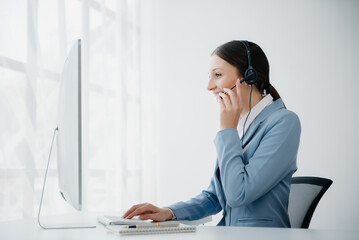 Serious call center operator in wireless headset talking with customer, woman in headphones with microphone consulting client on phone in customer support service in business center.