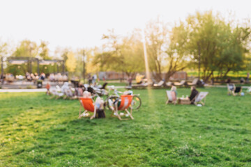 Blurred garden with lighting sunset. Public park with people. Blurred image of people in day in city park background - obrazy, fototapety, plakaty