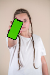 Teenage girl showing smartphone with green screen