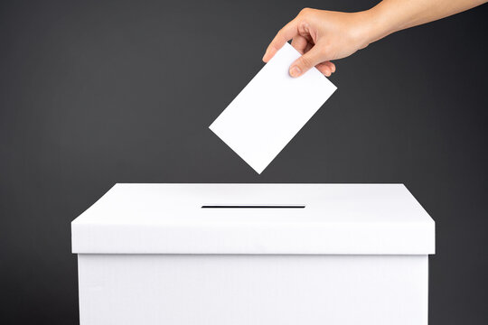Female voter holds vote ballot paper in her hand above vote ballot for casting vote on black background