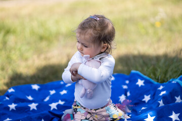toddler girl hugs rabbit toy on picnic blanket, authentic activity outdoor © skypictom