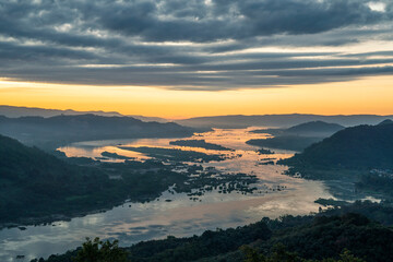 High-angle view of the Mekong River flowing through Laos and Thailand. The top of the mountain has morning fog covering the sky as the sun rises